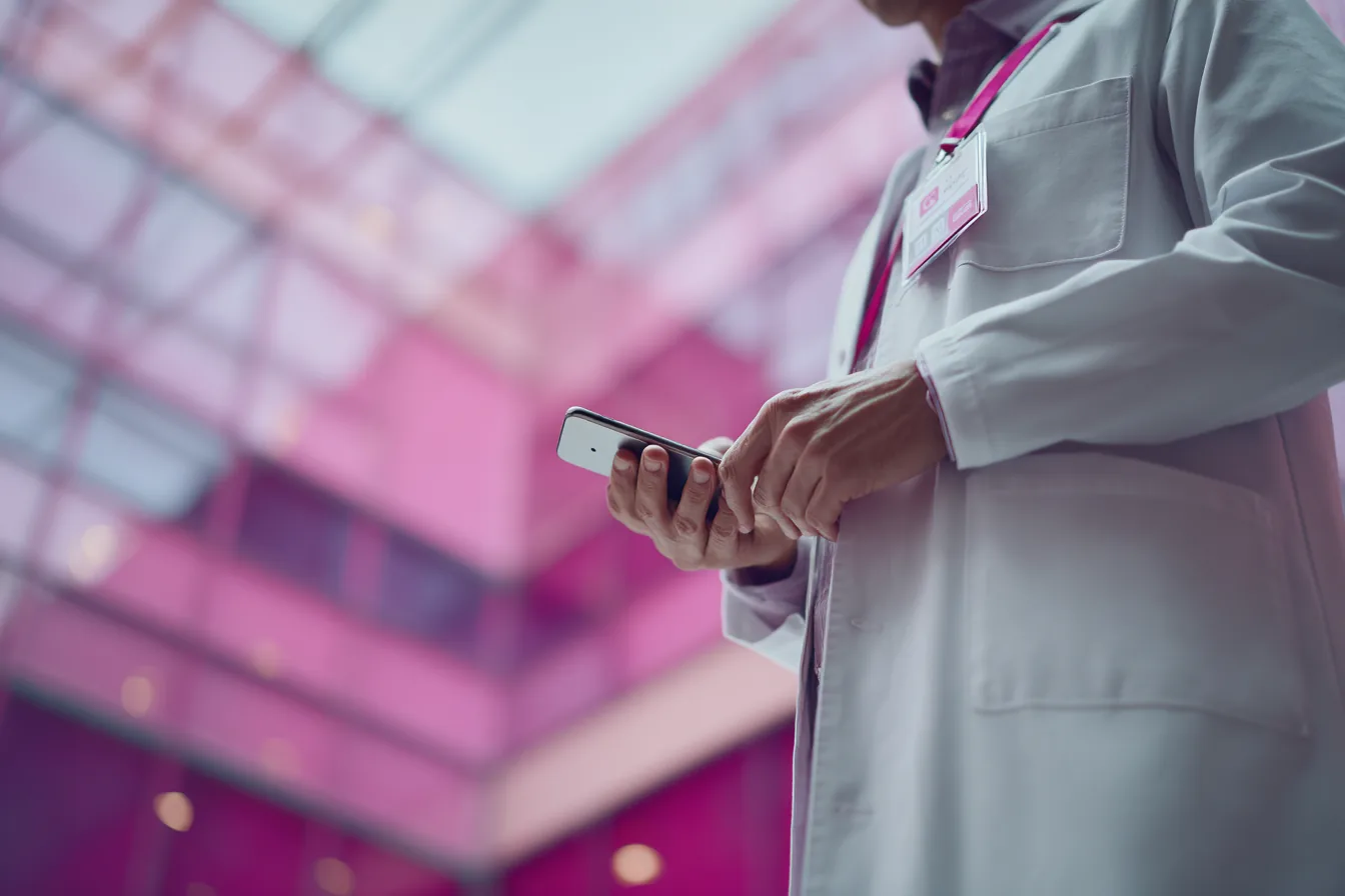 Physician reviewing data on mobile device in hospital corridor