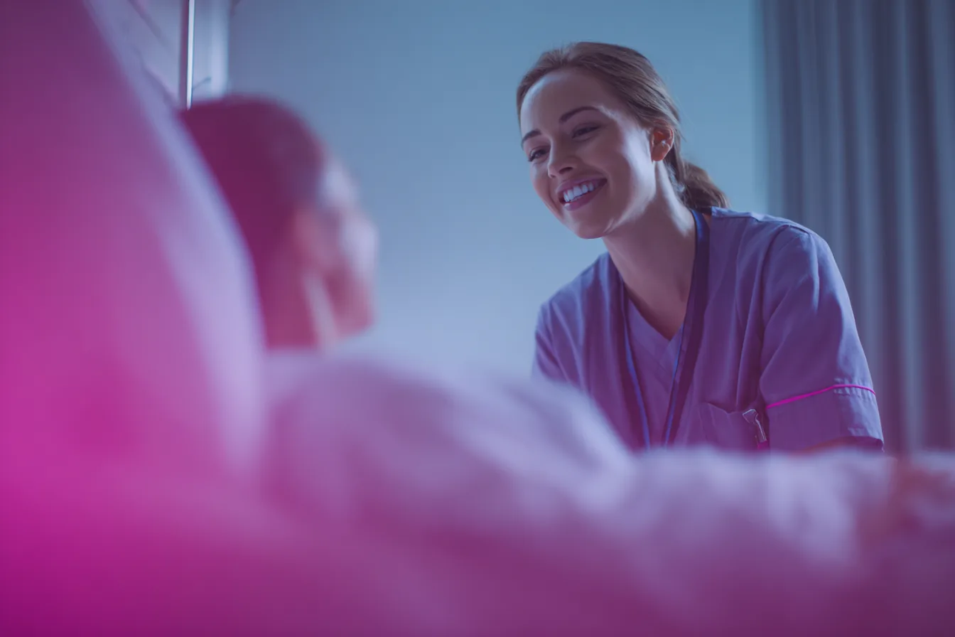 Nurse smiling while caring for a patient at the bedside